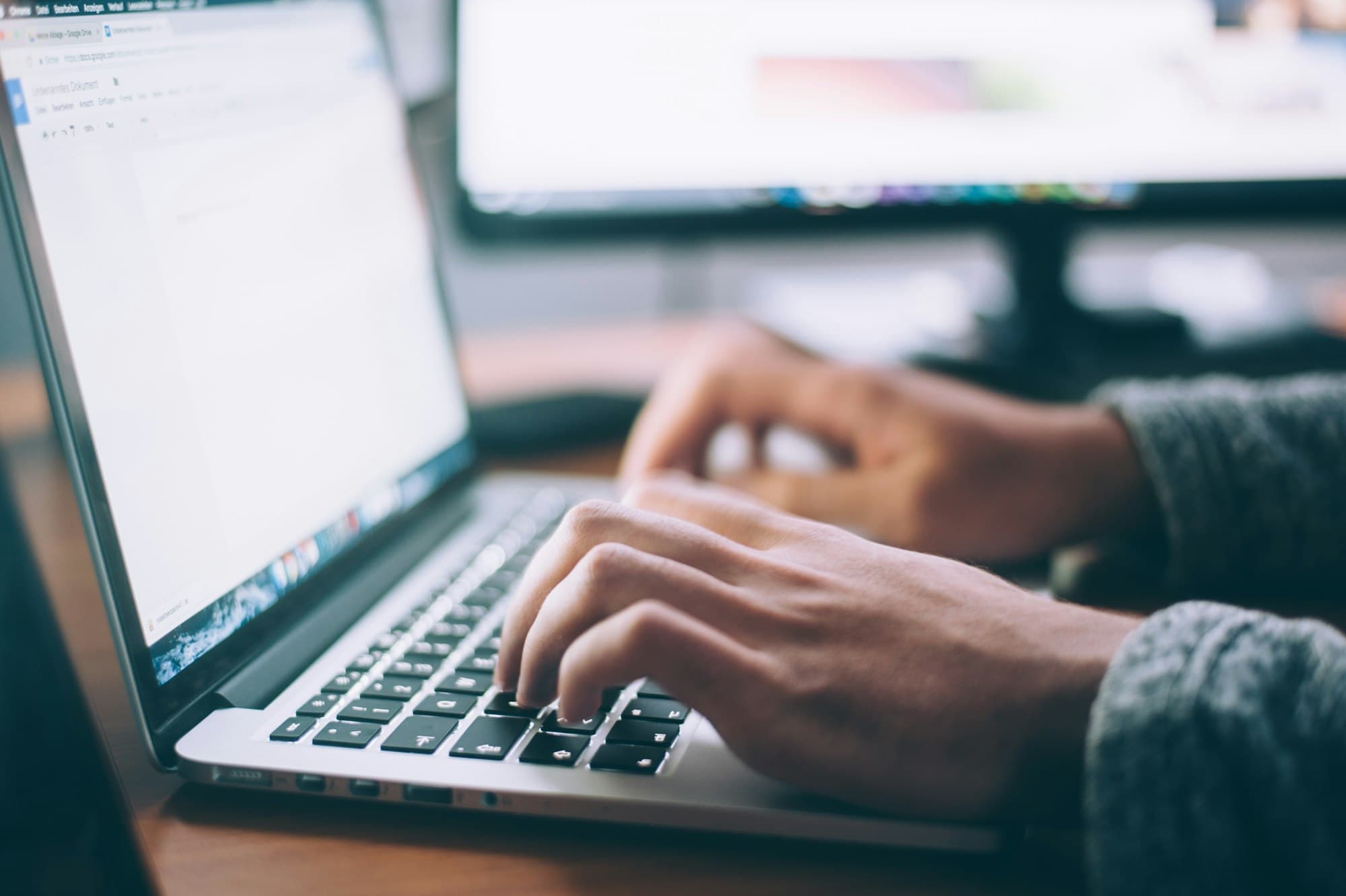 Hands on a laptop — the page still has to be written by someone who knows the work